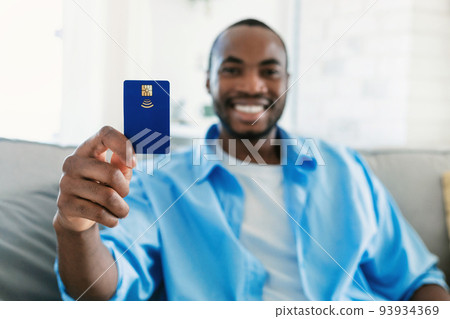 Excited black man showing credit card and smiling, recommending great bank service, selective focus 93934369