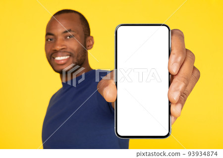 African American Guy Showing Large Cellphone Screen Over Yellow Background 93934874