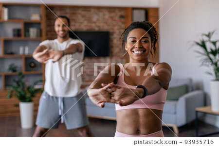 Happy young african american man and woman in sportswear doing stretching or warm up exercises Happy young african american man and woman in sportswear doing stretching or warm up exercises 93935716