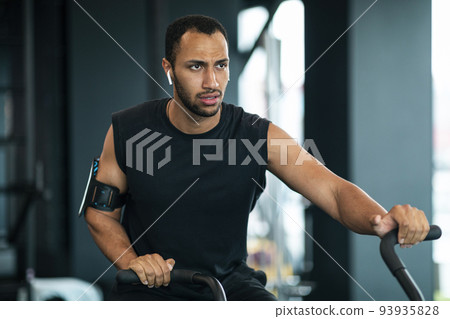 Motivated Black Man Using Elliptical Bike Machine While Training At Gym 93935828