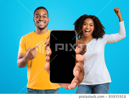 Glad emotional millennial african american couple celebrate victory with hands gesture, show big phone with empty screen 93935918