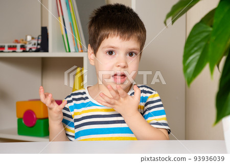 Preschool boy 4 years old bites his nails looking at the camera Preschool boy 4 years old bites his nails looking at the camera 93936039