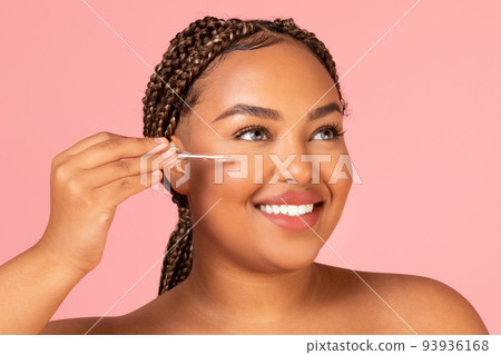African American Lady Applying Facial Serum Moisturizing Skin, Pink Background African American Lady Applying Facial Serum Moisturizing Skin, Pink Background 93936168