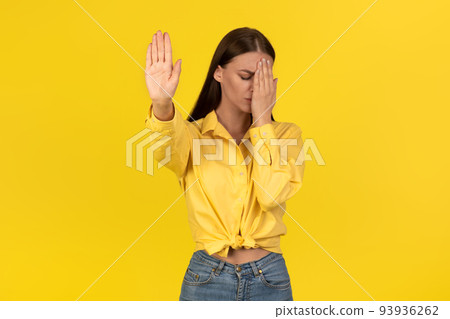 Female Gesturing Stop Covering Face With Hand Protesting, Yellow Background Female Gesturing Stop Covering Face With Hand Protesting, Yellow Background 93936262