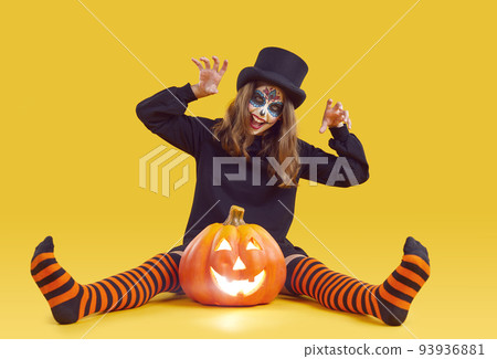 Cheerful preteen girl with Halloween makeup makes scratching gesture on orange background. Cheerful preteen girl with Halloween makeup makes scratching gesture on orange background. 93936881