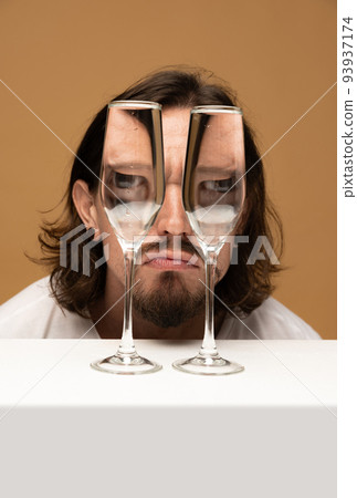 Happy man's face through wine glasses. Object distortion, optical illusion. Minimalistic contemporary art. 93937174