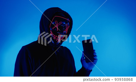 Digital security Concept. Anonymous hacker with mask holding smartphone hacked. Personal and Cyber data security in mobile phone stolen by man in mask. Represent digital privacy protection concept. Digital security Concept. Anonymous hacker with mask holding smartphone hacked. Personal and Cyber data security in mobile phone stolen by man in mask. Represent digital privacy protection concept. 93938868