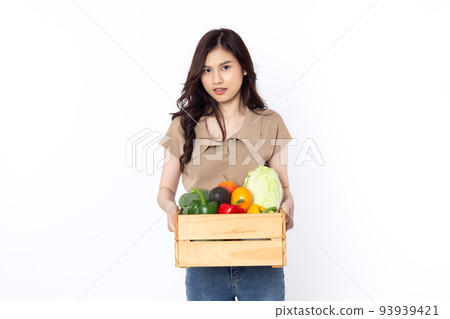 Cheerful smiling Asian woman holding a wooden box of vegetables after shopping isolated on a white background Cheerful smiling Asian woman holding a wooden box of vegetables after shopping isolated on a white background 93939421