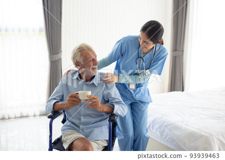 Young female nurse explaining information to disabled patients in wheelchairs., Retirement health check-up doctor concept at home. 93939463