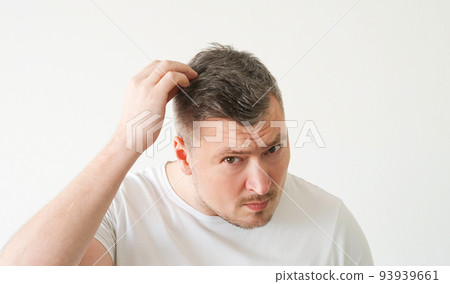 Vertical video. Male care. Middle-aged man. Stylish look. Concentrated guy touching gray hair checking scurf on head posing white background. 93939661