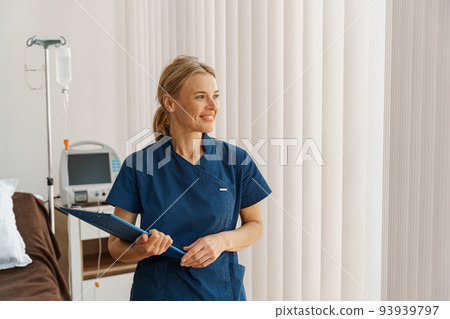 Portrait of smiling nurse holding tablet while stands in hospital ward and looking away 93939797