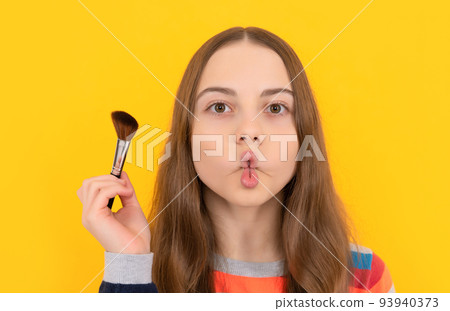 Portrait of kid making funny fish lips face holding powder brush for applying cosmetics, makeup Portrait of kid making funny fish lips face holding powder brush for applying cosmetics, makeup 93940373