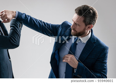 Aggressive professional man businessman punch coworker with fist grey background, fight Aggressive professional man businessman punch coworker with fist grey background, fight 93940601