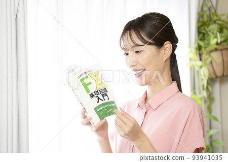 一個拿著外匯書籍的女人對著窗戶微笑 一個拿著外匯書籍的女人對著窗戶微笑 93941035