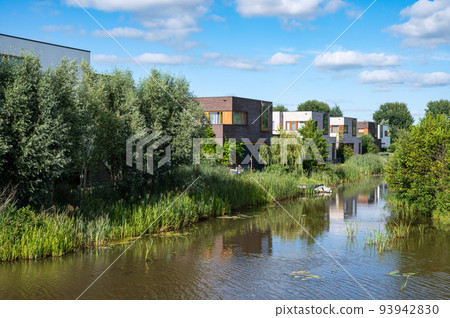 Groningen, The Netherlands, Contemporary country style houses at the waterfront surrounded by nature over blue sky in the suburbs 93942830