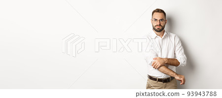 Angry man roll up sleeves and looking offended, getting ready to fight, standing over white background Angry man roll up sleeves and looking offended, getting ready to fight, standing over white background 93943788