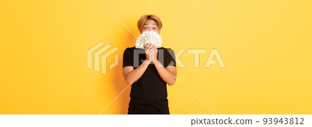 Excited lucky blond asian guy rejoicing from winning cash, holding money and looking happy, standing yellow background Excited lucky blond asian guy rejoicing from winning cash, holding money and looking happy, standing yellow background 93943812
