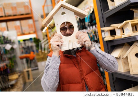 customer in garden supply store fooling around with birdhouse customer in garden supply store fooling around with birdhouse 93944933