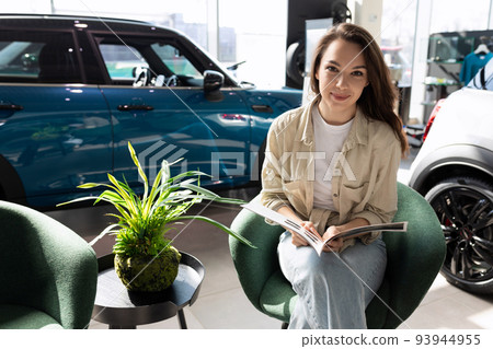 young happy woman in new car dealership showroom 93944955