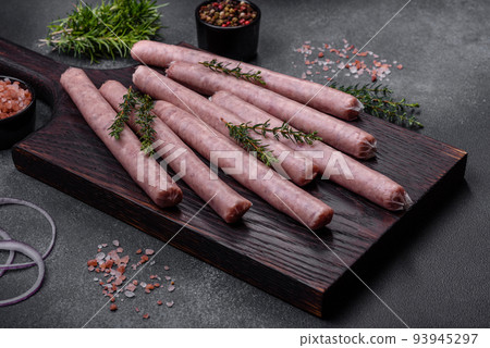 Raw sausages with spices on a wooden cutting board on a stone background with copy space for your text Raw sausages with spices on a wooden cutting board on a stone background with copy space for your text 93945297