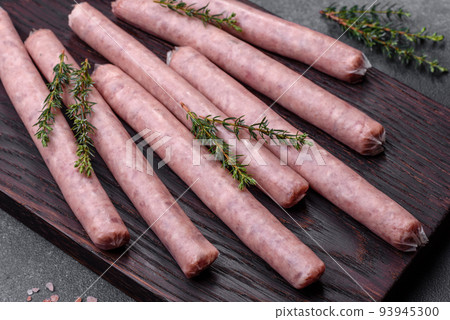 Raw sausages with spices on a wooden cutting board on a stone background with copy space for your text Raw sausages with spices on a wooden cutting board on a stone background with copy space for your text 93945300