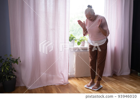 Woman stepping on floor scales, closeup. Weight control 93946010