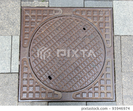 Old rusty sewer hatch on an old metal plate. View from above. 93946974
