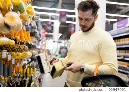 a customer holds a bubble level in his hands in a store of building materials and finishing fixtures 93947061