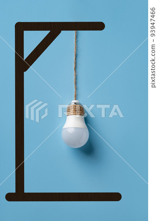 Light bulb hanging from gallows over blue background. Deindustrialization and regression concept. 93947466
