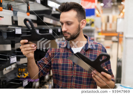 Buyer at hardware store chooses tools for plastering wall putty 93947969