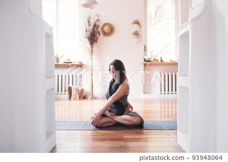 Woman practicing yoga lesson, breathing, meditating, doing Twisted Padmasana Woman practicing yoga lesson, breathing, meditating, doing Twisted Padmasana 93948064