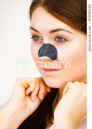Woman applying pore strips on nose Woman applying pore strips on nose 93948100