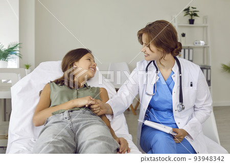 Friendly, supportive pediatrician and a happy teenage child holding hands and smiling 93948342