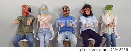 Group of happy strange men and women wearing funny animal masks showing thumbs up 93948386