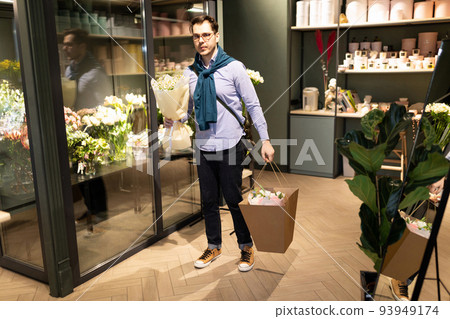 young man satisfied with the service of the florist shop with bouquets in his hands young man satisfied with the service of the florist shop with bouquets in his hands 93949174