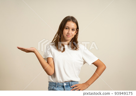 Presentation and people concept - happy smiling young teenage girl holding something on empty hand over beige background. Presentation and people concept - happy smiling young teenage girl holding something on empty hand over beige background. 93949175