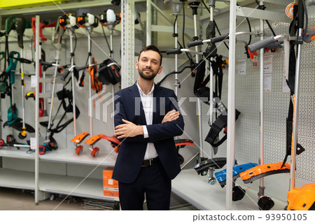 friendly successful shop manager selling garden trimmers for mowing grass 93950105