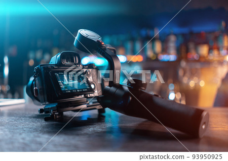 portable handheld video gimbal with mirrorless dslr camera on wooden table 93950925