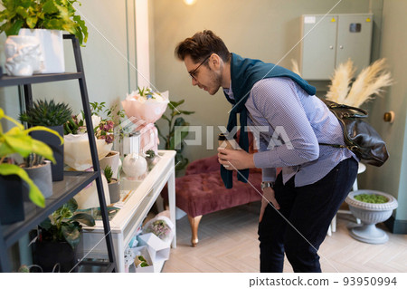 a man examines the assortment in a flower and bouquet shop before buying 93950994