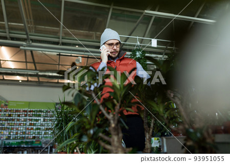 a customer in a gardening store Choose a potted plant speaks on the phone a customer in a gardening store Choose a potted plant speaks on the phone 93951055