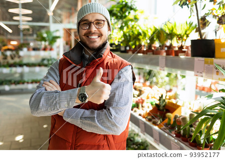 a sales assistant in a gardening goods store looks at the camera with a smile and shows a like 93952177