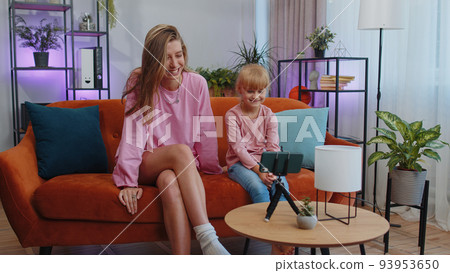 Blogger mother and child kid daughter listening music, dancing, recording video social media content Blogger mother and child kid daughter listening music, dancing, recording video social media content 93953650