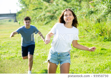 Laughing teenagers playing outdoors funning at grass on day 93958730