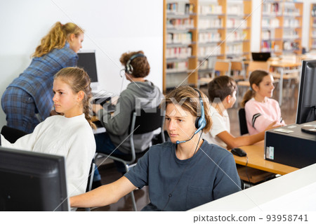Teenage student in headphones at the computer in school class 93958741