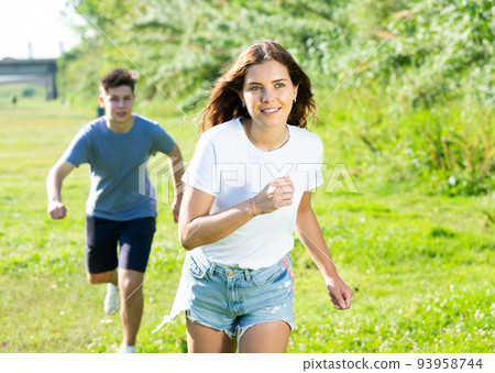 A couple of young people is running on the grass A couple of young people is running on the grass 93958744