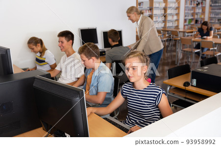 Schoolgirl using computer and teacher teaching she Schoolgirl using computer and teacher teaching she 93958992