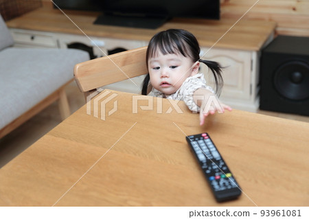 A 1-year-old girl pranking the TV remote control 93961081