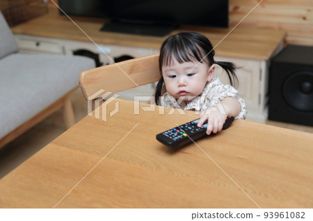 A 1-year-old girl pranking the TV remote control A 1-year-old girl pranking the TV remote control 93961082