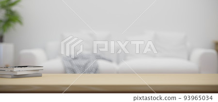 Copy space on a wood coffee table over blurred minimal white couch in living room in the background 93965034