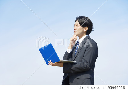 Businessman thinking with a laptop blue sky background 93966628